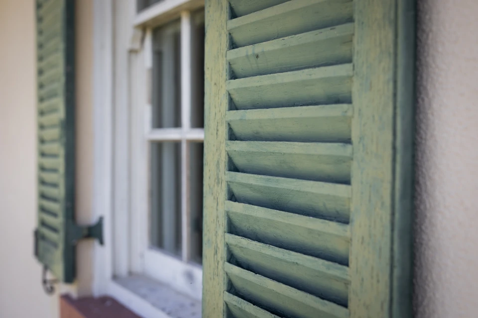 Façade extérieure d'un bâtiment méditerranéen avec volets battants bleu clair fermés
