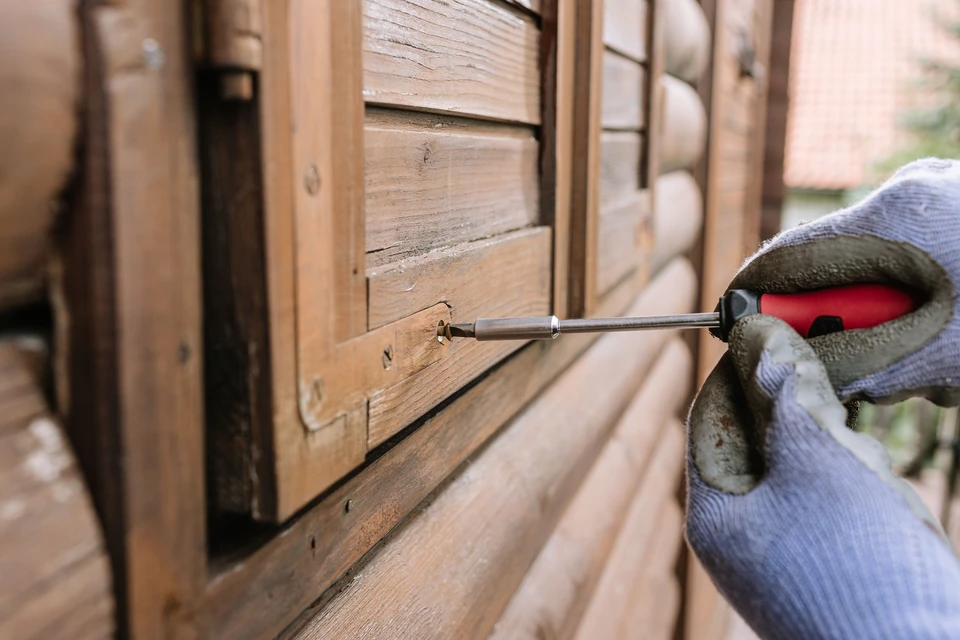 Ouvrier en tenue bleue et casquette installant une porte en bois dans un intérieur résidentiel en construction