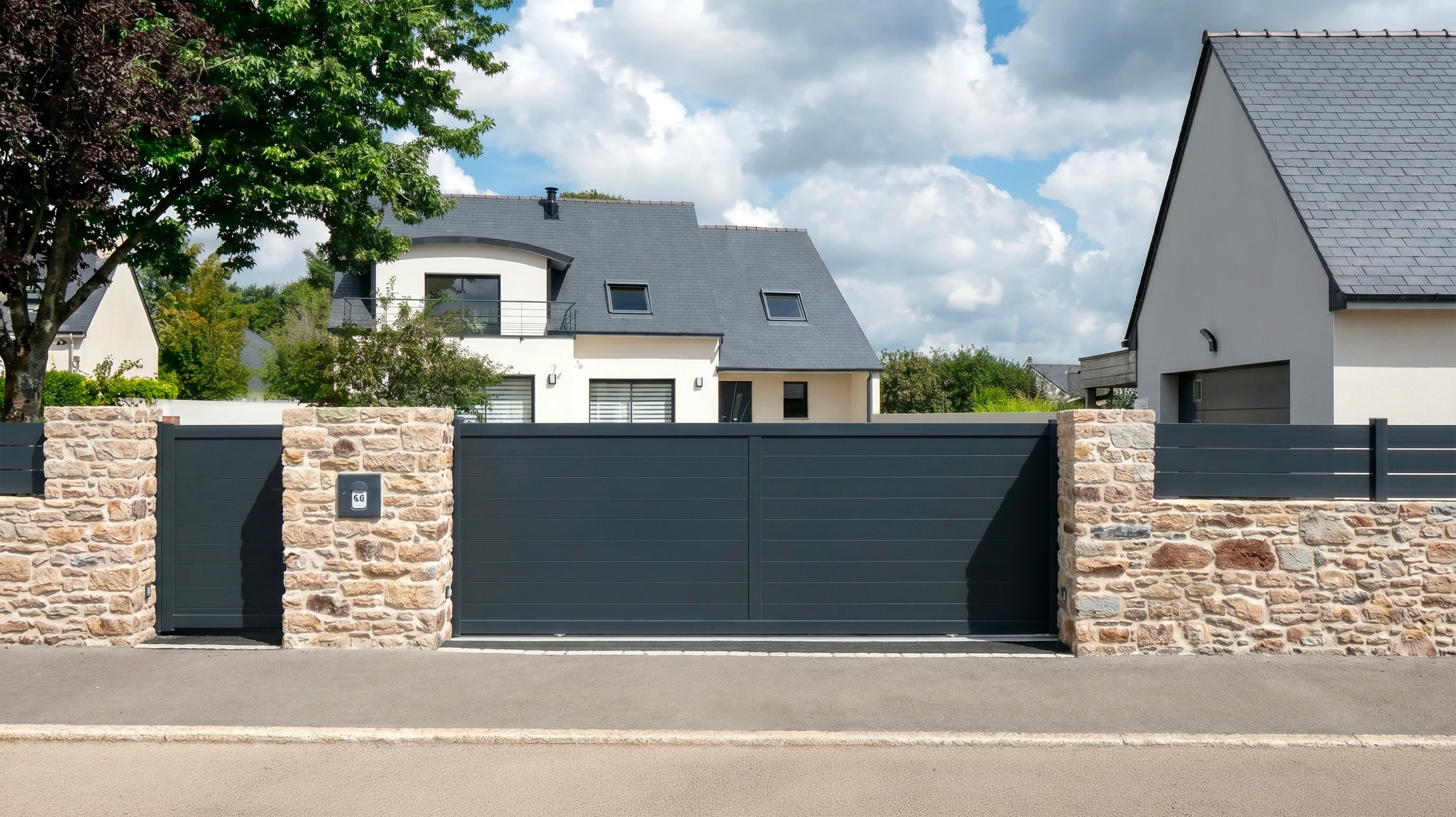 Une main tient une télécommande de portail électrique devant une clôture en bois et un portail fermé